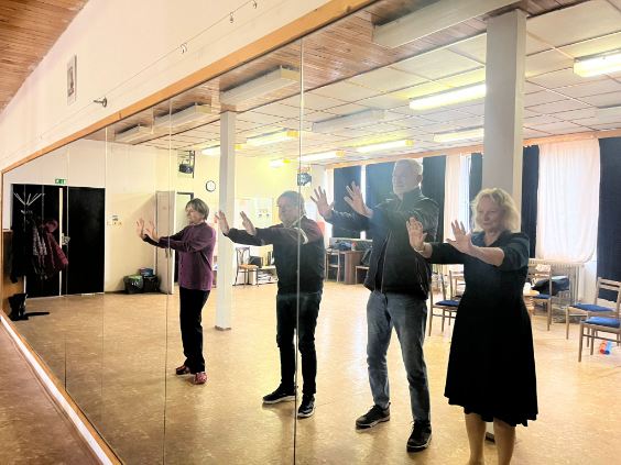 Účastníci divadelného workshopu počas výuky - dvaja muži a dve ženy s rukami pred sebou stoja pred zrkadlom.