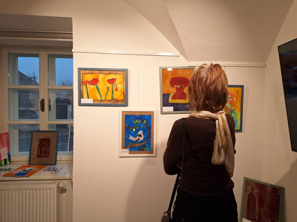 Žena prezerajúca si výstavu obrazov vysiacich na stene. 