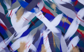 Abstraktný obraz z bielych, tmavomodrých, bielych a červených škvŕn vytvorený z ovčej vlny.