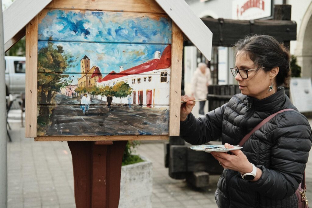 Fotografia Michaely Syrovej ako maľuje knižnú búdku.