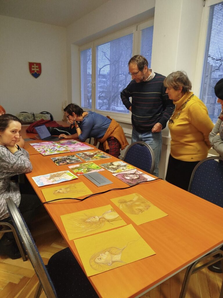 Tri ženy a jeden muž konzultujú výtvarné diela. 