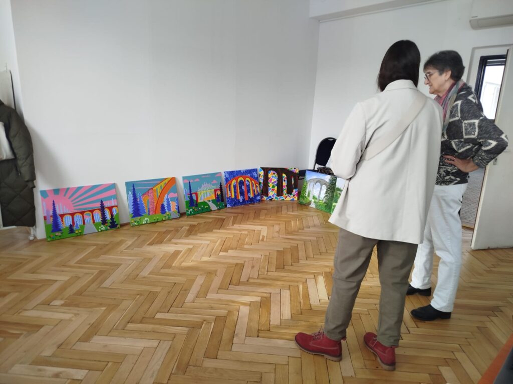 Dve ženy prezerajú výtvarné diela.