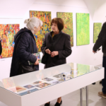 Dve staršie ženy prezerajúce si výstavu.