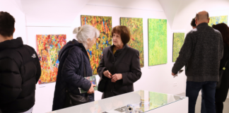 Dve staršie ženy prezerajúce si výstavu.