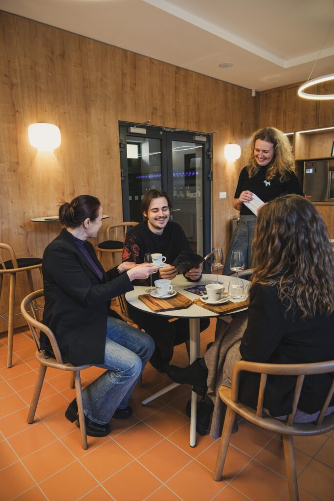 Jeden muž a dve ženy smejúci sa v kaviarni.