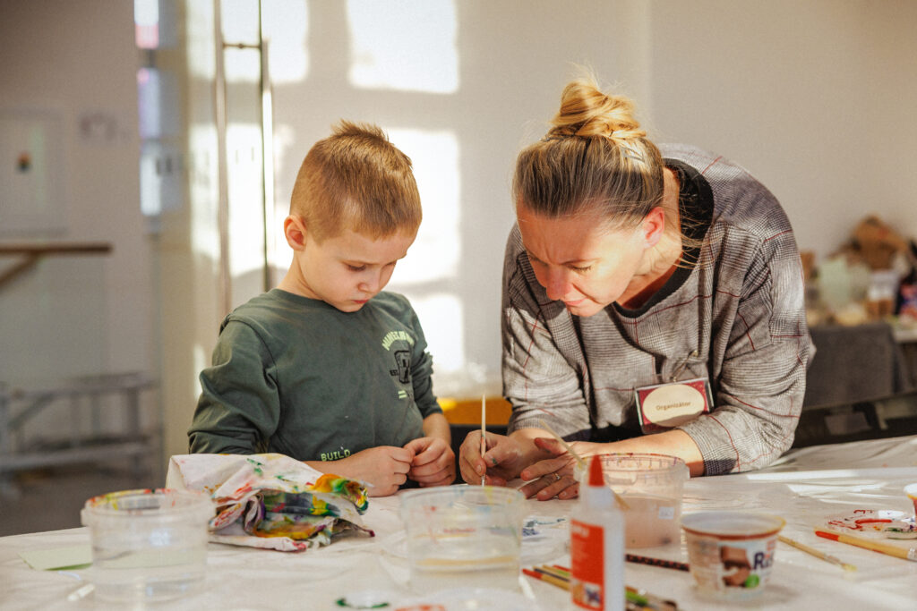 Žena pomáhajúca dieťaťu tvoriť. 