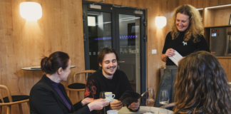 Jeden muž a dve ženy smejúci sa v kaviarni.