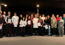 Súťažiaci a porotcovia stojaci na pódiu