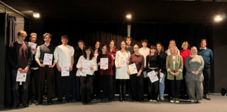 Súťažiaci a porotcovia stojaci na pódiu