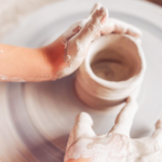 Ruky modelujúce z hliny hrnček.