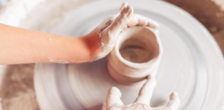 Ruky modelujúce z hliny hrnček.