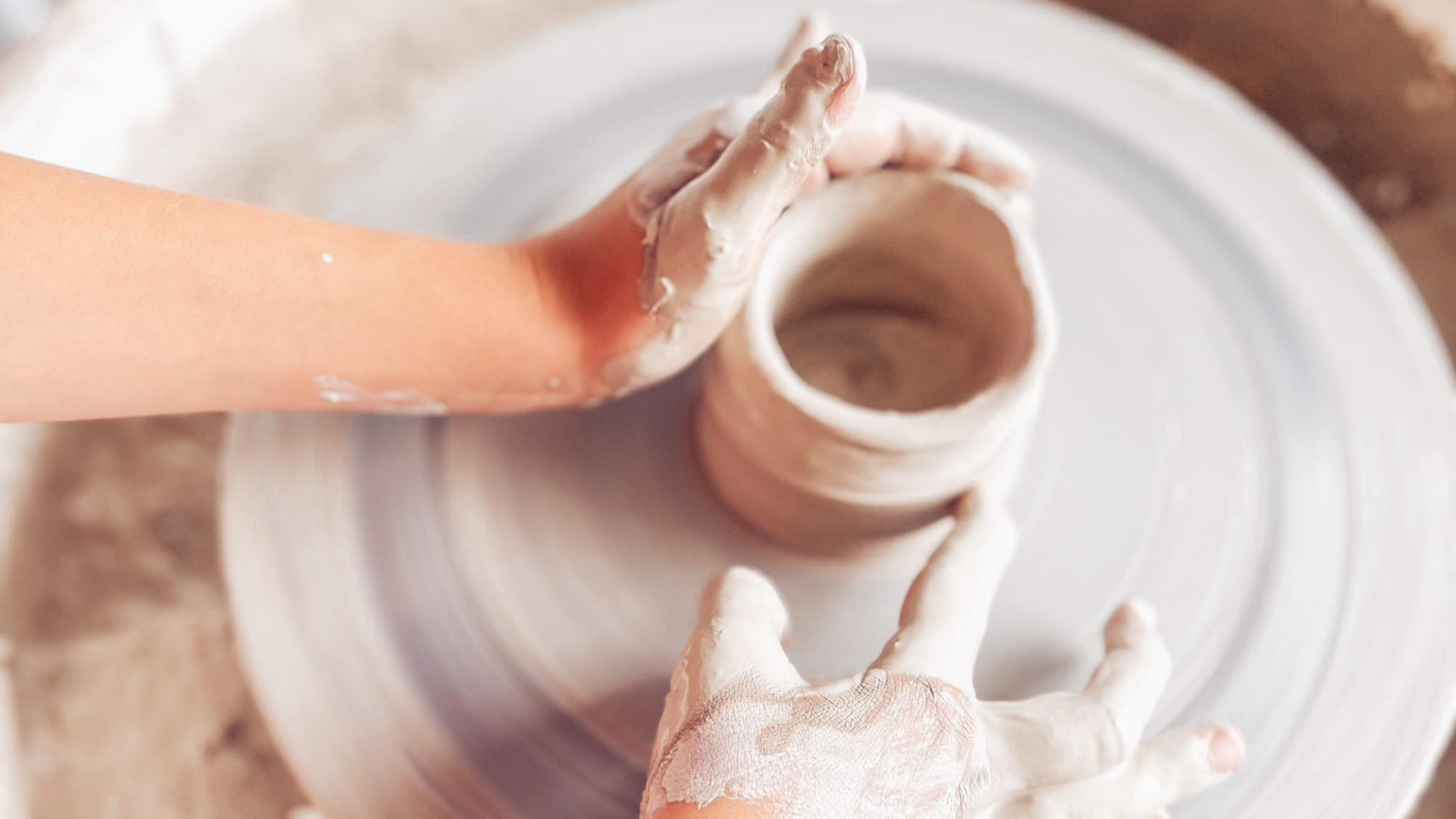 Ruky modelujúce z hliny hrnček.