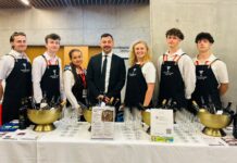Dve ženy a päť mužov ponúkajúcich víno
